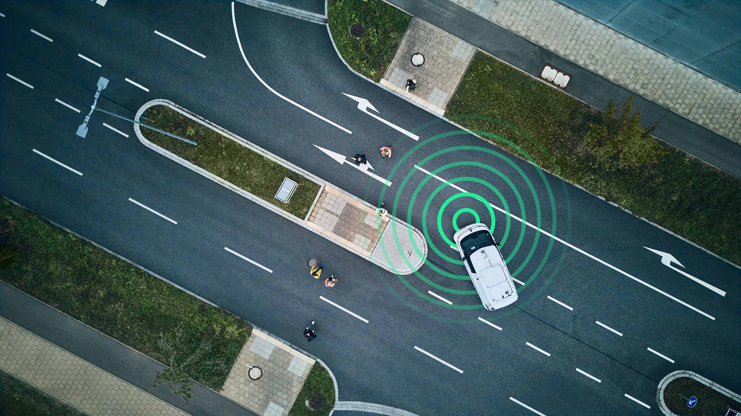 Aerial view of white car using radar sensors near pedestrian crossing, illustrating automated driving and object detection technology