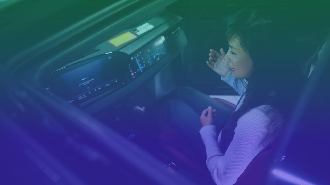 Person in passenger seat of a car with dashboard and infotainment system visible