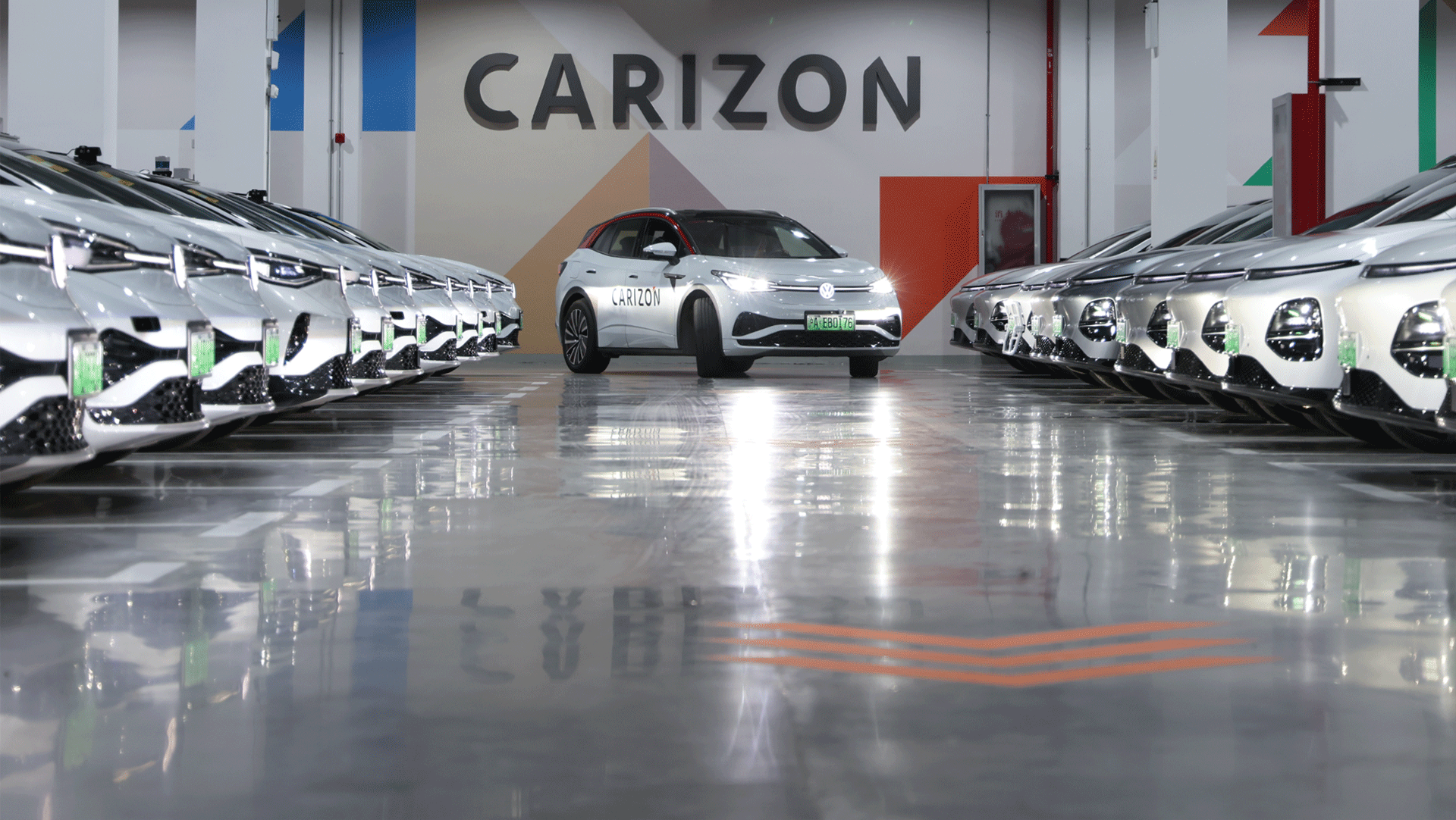 In a sleek indoor space, a lineup of white vehicles surrounds a central car branded “CARIZON,” set against a geometric backdrop.