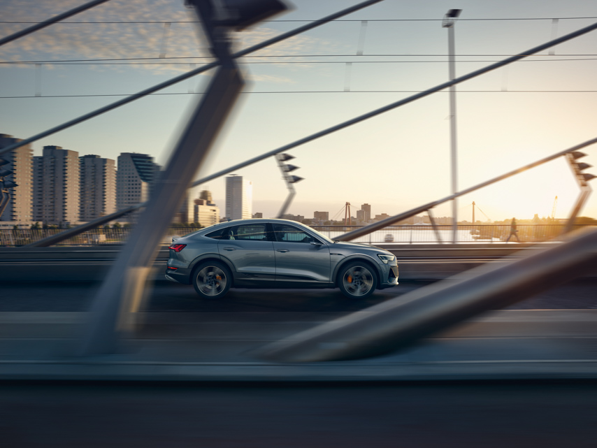 The Audi e-tron Sportback driving on a bridge at sunset