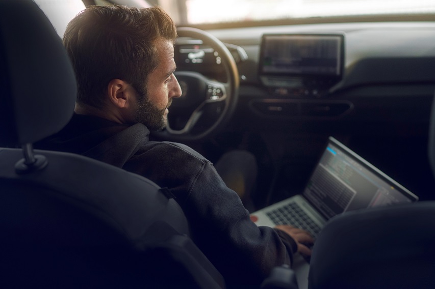 men in electric car with laptop