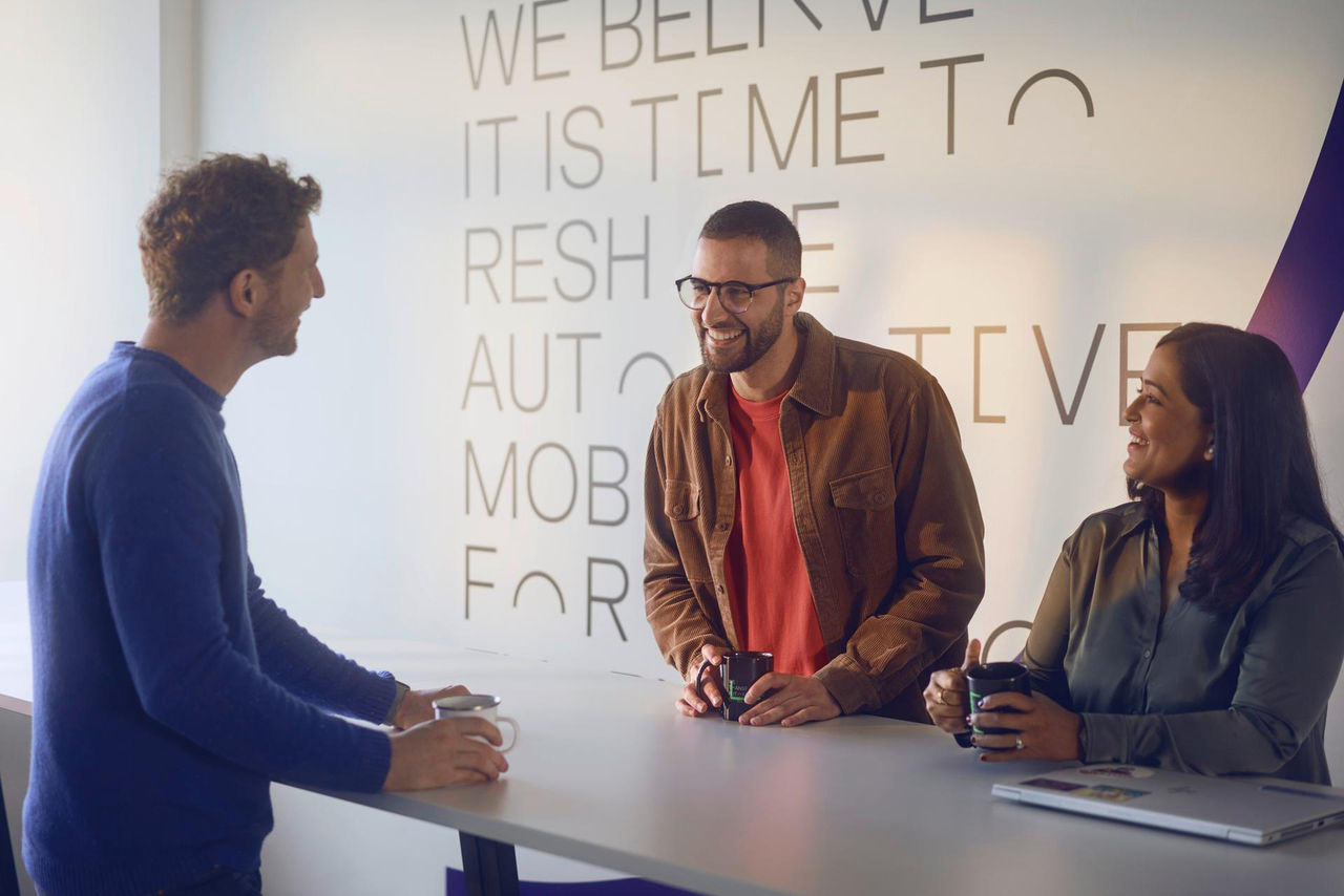 Colleagues standing together in an office kitchen, talking and connecting in an open and respectful work environment.
