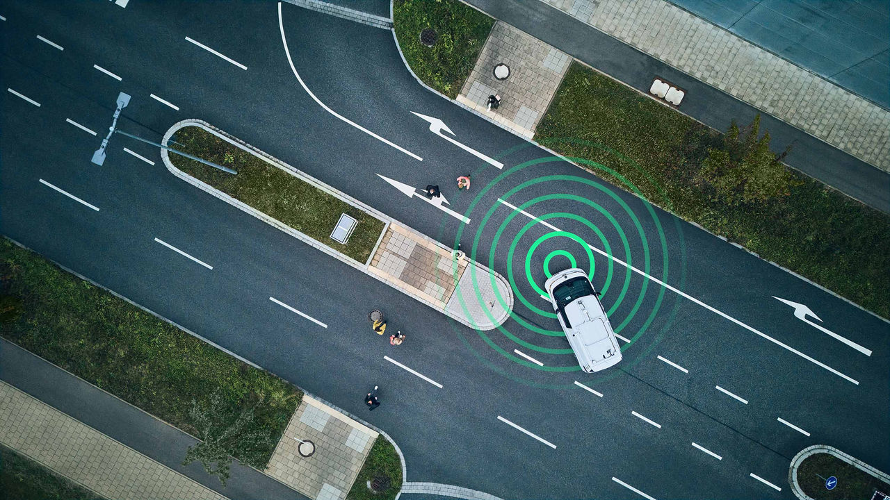 Enhancing automated driving safety with innovative testing methods Aerial view of white car using radar sensors near pedestrian crossing, illustrating automated driving and object detection technology