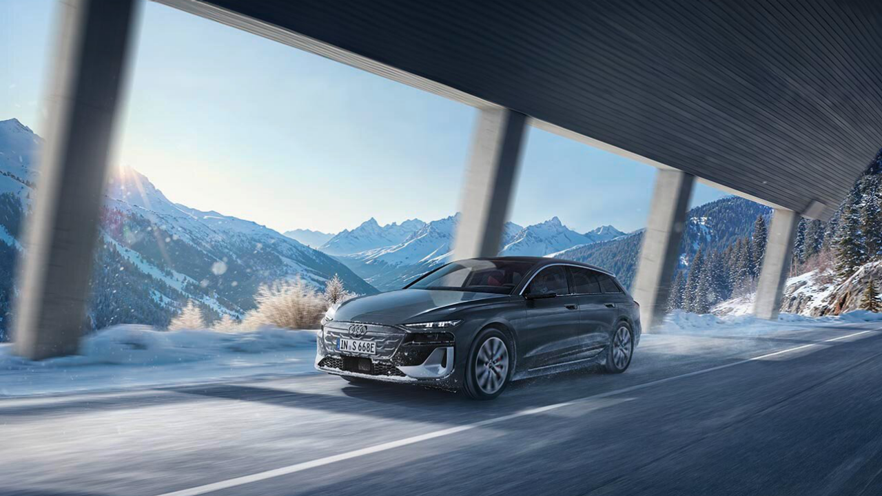 Volkswagen sedan driving on a snow-covered mountain road under a modern avalanche protection structure, showcasing winter performance, safety, and scenic alpine landscape.